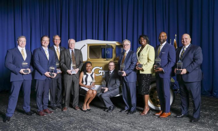 a group of people with awards pose with the Ramblin' Wreck