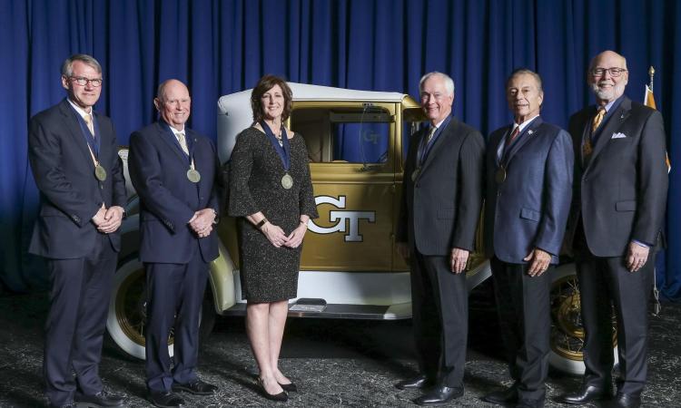 a group of people with awards pose with the Ramblin' Wreck