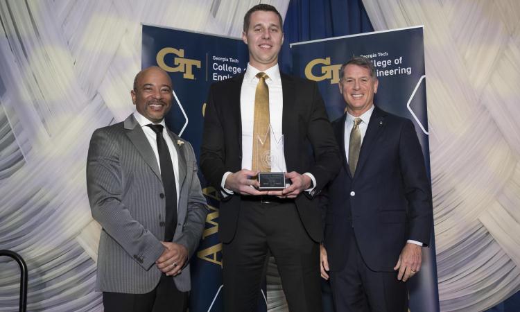 two winners from the 2025 Alumni Awards posing with the Dean of Engineering