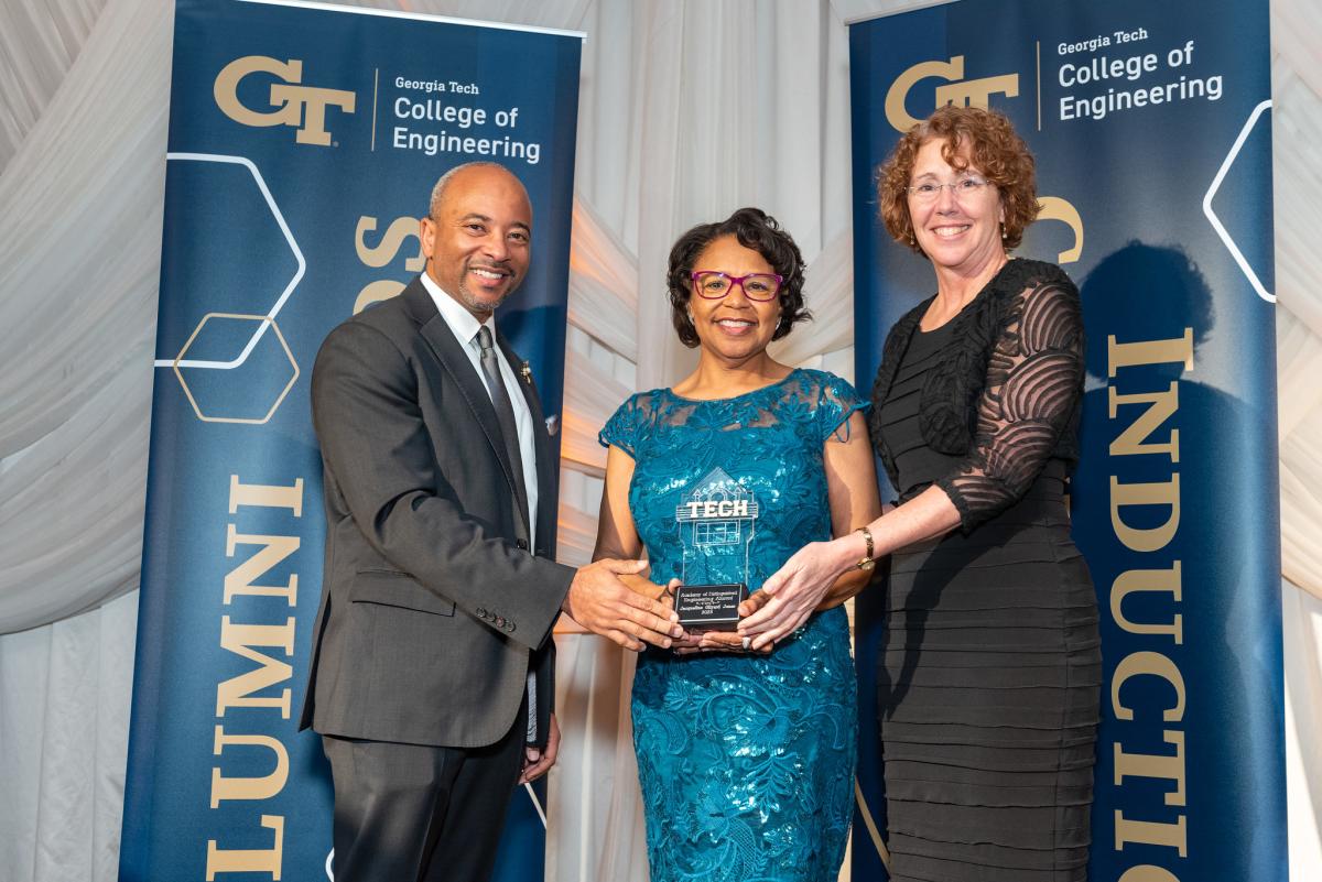 Raheem Beyah stands with Jacqueline Gilyard Jones and Sandy Magnus holding a trophy